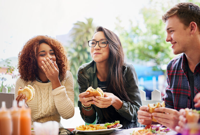 three friends eating burgers