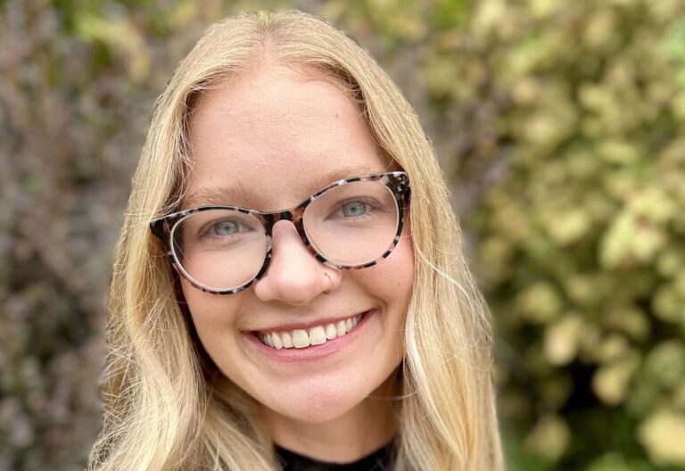 Charlotte Rogus, a young woman with blond hair, stands infront of green background. She is a eating disorders Registered Dietitian in Raleigh, Cary and Chapel Hill.